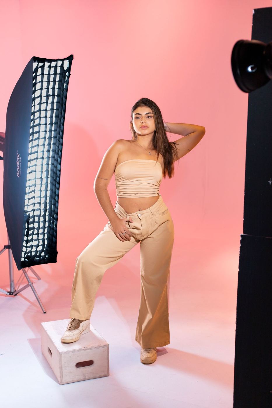 Modelka pozuje w studiu na różowym tle obok softboxa